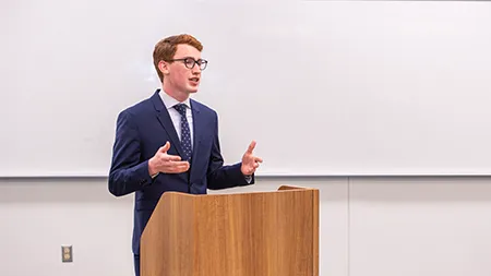 Cedarville University student delivers speech at podium during classroom presentation.