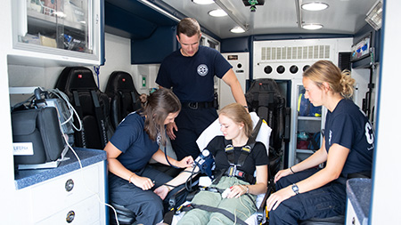 EMS student workers with a patient in the UMS vehicle