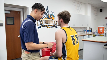 Athletic training student treating basketball player