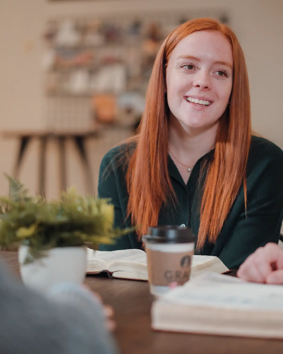 Cedarville student smiling during Bible study with open Bible and coffee cup