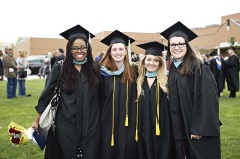 Four students in cap and gown at commencement