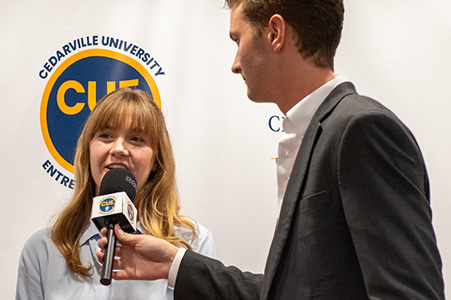 Man interviewing women with the Cedarville University Entrepreneurship CUE logo in the background