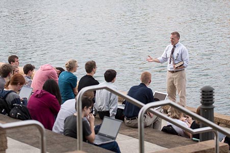 students on the steps of the BTS with a professor teaching with the lake in the background