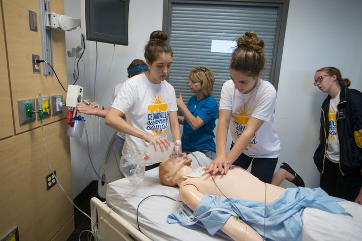 Two female students practice CPR on a mannequin