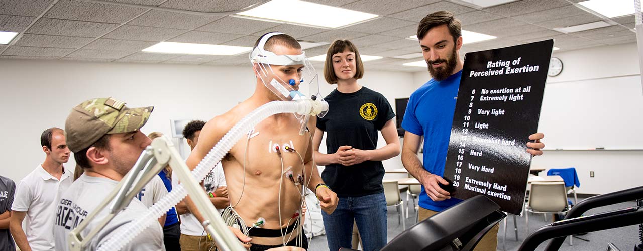 Male allied health student runs on treadmill while sensors record data
