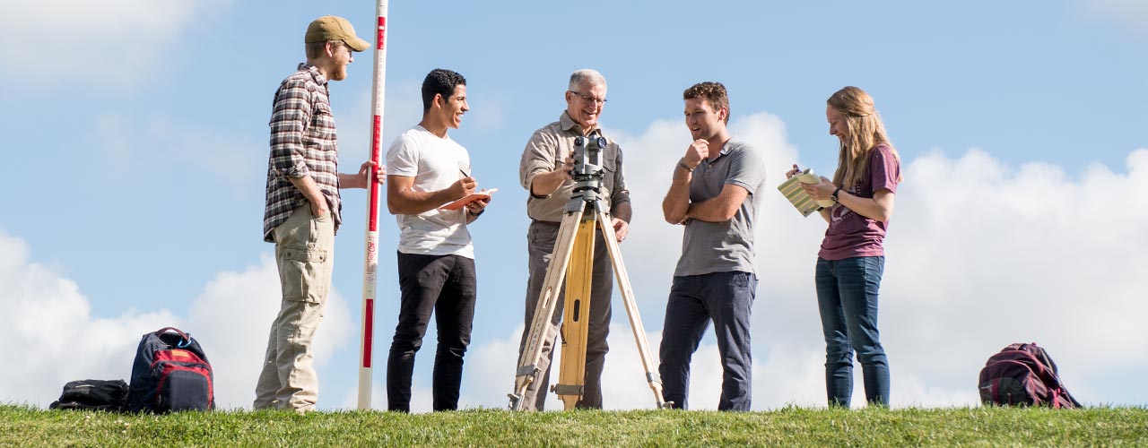 Five people surrounding a surveyors tool