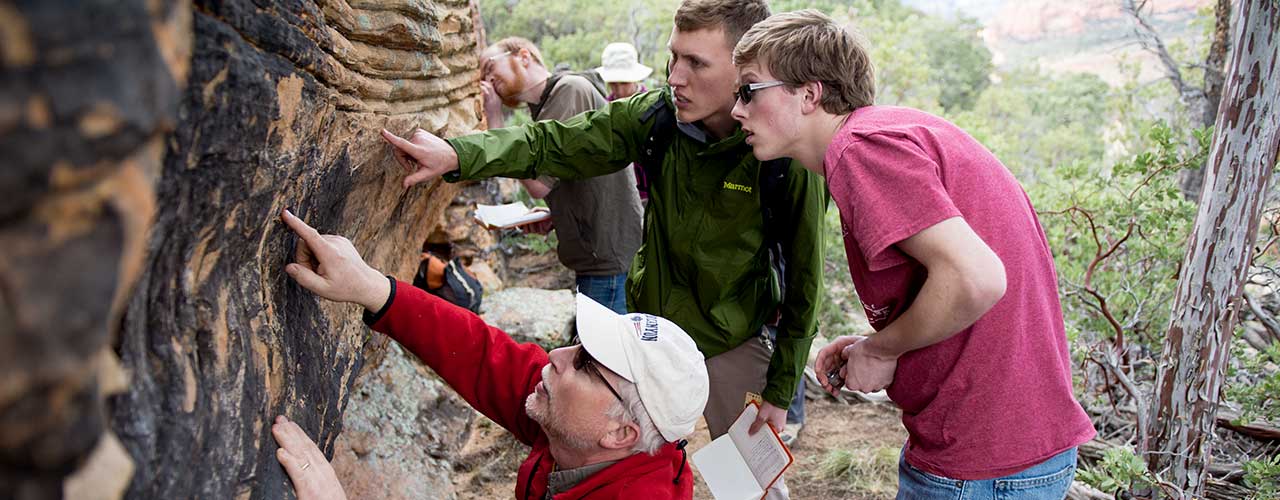 Professor and two geology students examine rock layers