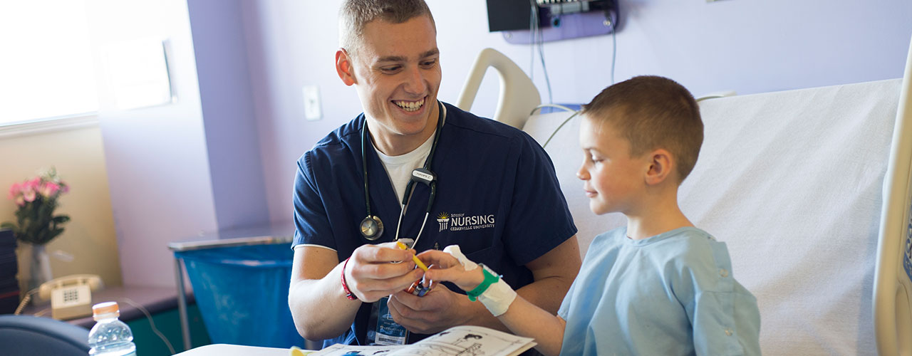 Male nursing student helps small child in hospital.