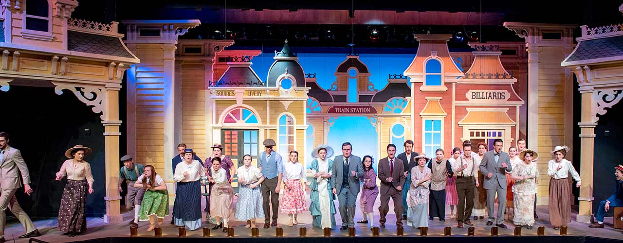 The cast of a Cedarville stage production performs in front of elaborate background