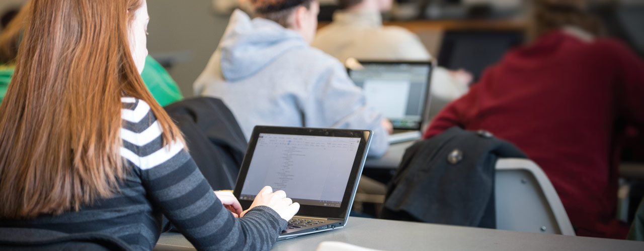 Female student takes notes on laptop in class