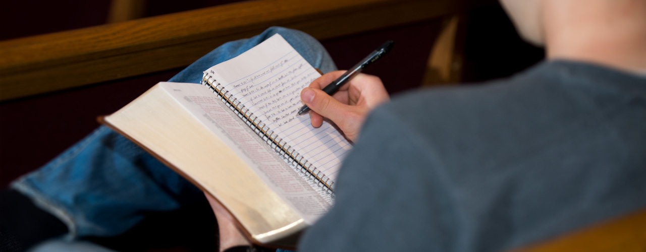 A student takes notes during chapel