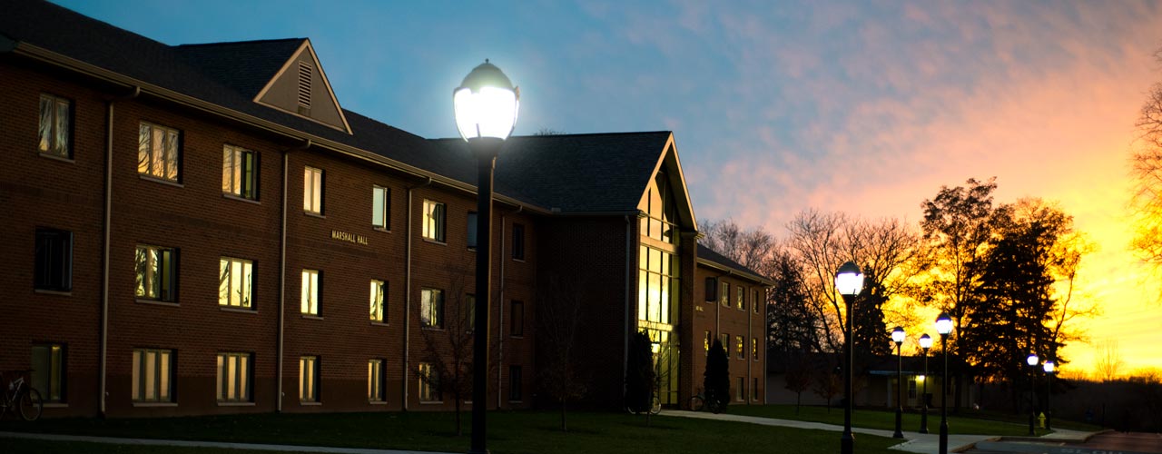 A men's dorm is silhouetted against the sunset
