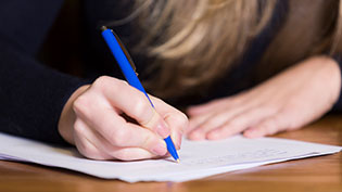 Closeup of a girl writing notes on paper.