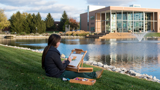 A female student paints by the lake