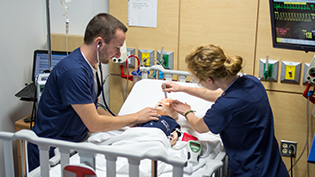 Male and female nursing students work in the simulation lab