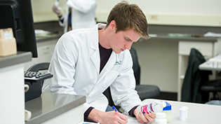Male pharmacy student reads a label on a bottle