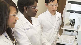 Pharmacy people in white lab coats standing working with equipment
