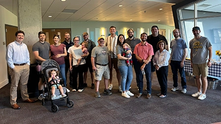 school-of-pharmacy-alumni-gathering Group of alumni and family members posing together indoors at a gathering, smiling for a group photo.