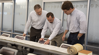 Image of 3 professors looking at Torah Scroll