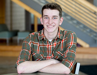 Noah Branch sits at a table in the Biblical and Theological Studies building