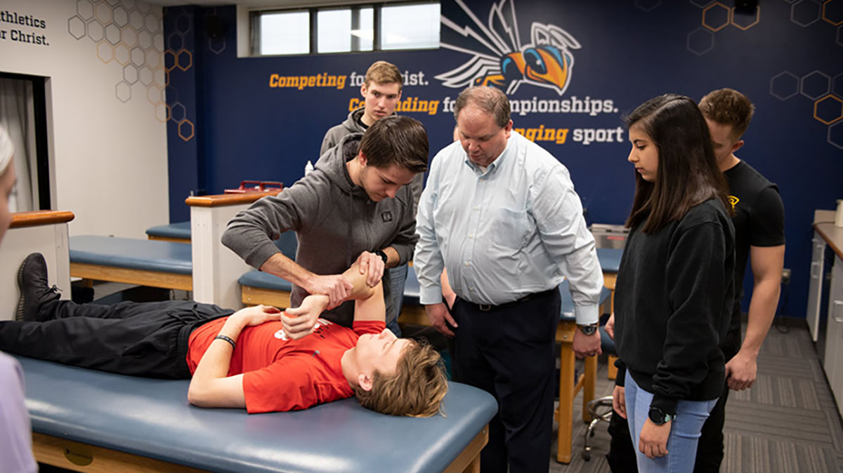 Students watching athletic training professor demonstrate procedure.