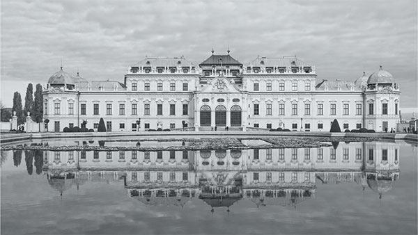 Large European palace reflecting in a lake.