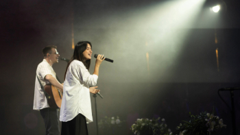 A man and woman lead worship on stage.