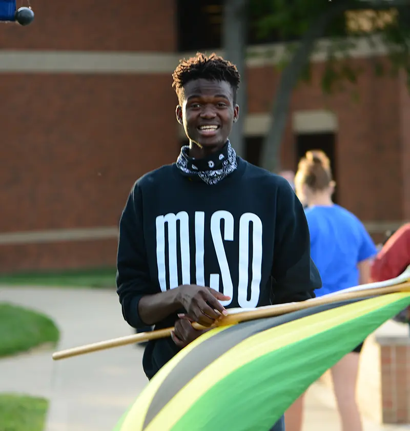 Guy with MISO sweatshirt standing, holding the Jamaican flag
