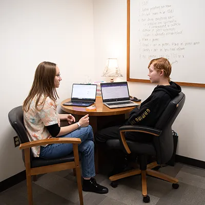 Female student seated at a table working on a laptop computer.