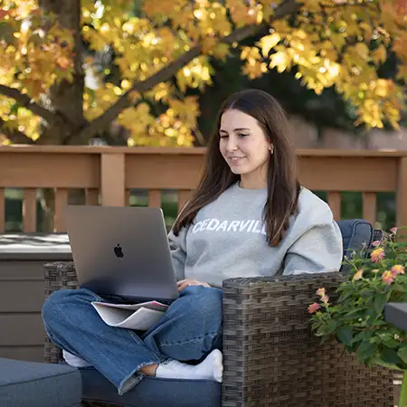 online undergraduate student on laptop sitting outside on a bench