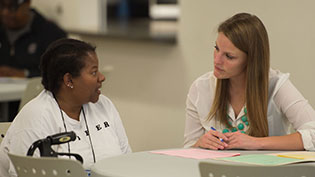 Female patient and female nurse sitting at a table completing paperwork.