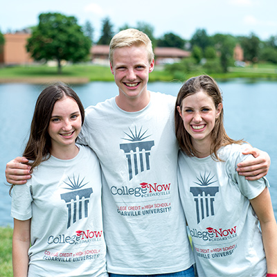Three college now students stand by lake