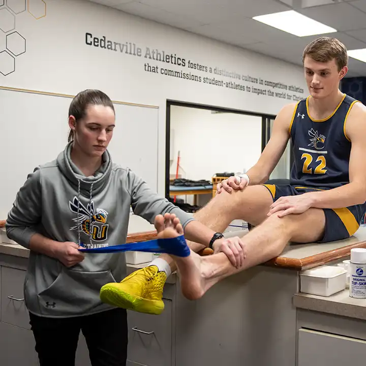 Female athletic trainer wrapping an athlete's ankle in the training room.
