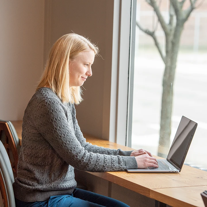 Woman sitting at desk by a window working on a laptop