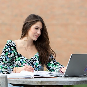 Girl studying with computer at a table outside