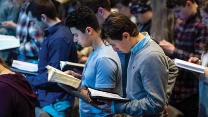 Cedarville students reading Bibles in chapel. 