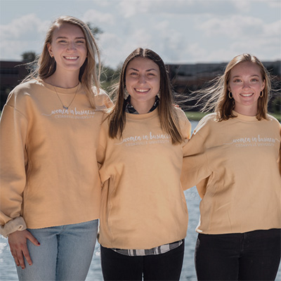 3 college students wearing Women in Business sweatshirts