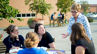 Professor talks to students at a table