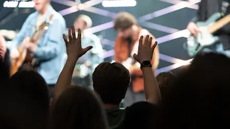 Student raising hands to praise God during chapel service
